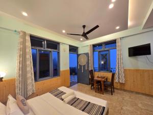 a bedroom with two beds and a desk and a tv at Aangan Royal Stay in Dharmsala