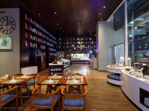 a restaurant with tables and chairs and a counter at Mercure Jakarta Simatupang in Jakarta