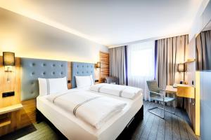 a hotel room with a large bed and a desk at Premier Inn Lindau in Lindau