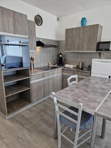 une cuisine avec des armoires en bois et une table et des chaises dans l'établissement Bord de mer avec piscine intérieure chauffée, à Port-la-Nouvelle