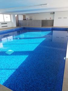 - une grande piscine revêtue de carrelage bleu dans l'établissement Bord de mer avec piscine intérieure chauffée, à Port-la-Nouvelle