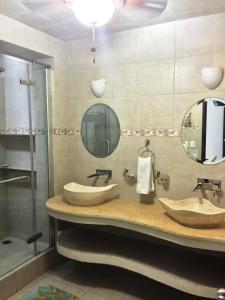 a bathroom with two sinks and two mirrors at Villa Costa Chica Comodisimo piscina gigante jardines in Acapulco