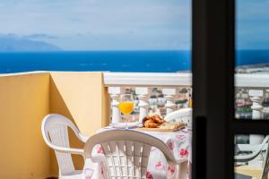 a table with a glass of orange juice on a balcony at Penthouse with ocean views - Torviscas in Adeje
