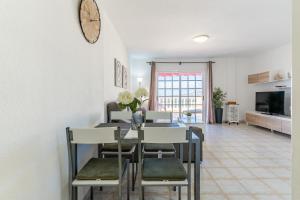 a dining room table with chairs and a clock on the wall at Penthouse with ocean views - Torviscas in Adeje