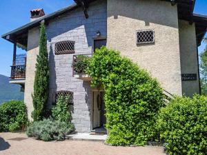 a brick house with a door and some bushes at Casa Marica in Porto Valtravaglia