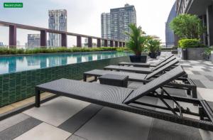 une rangée de tables et de chaises sur un bâtiment avec une piscine dans l'établissement Noble Remix Thonglor - Direct BTS Access - Super Fast Wi-Fi, à Bangkok
