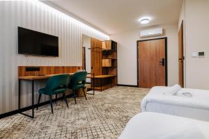 a hotel room with a bed and a desk and a tv at Hotel Cztery Pory Roku in Głogów Małopolski