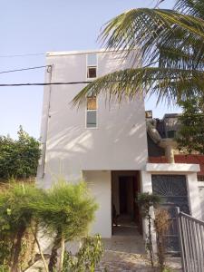 a white house with a palm tree in front of it at Rabbi Chambres in Mbour