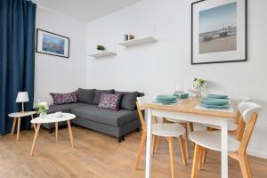 een woonkamer met een bank en een tafel bij Modern Apartment with Historic Shipyard Views and Parking by Noclegi Renters in Suchanino