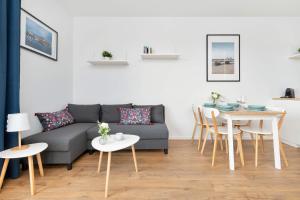 een woonkamer met een bank en een tafel bij Modern Apartment with Historic Shipyard Views and Parking by Noclegi Renters in Suchanino +23 foto's