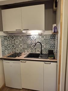 a kitchen with white cabinets and a sink at Petit ours I N10 2P5 in Marcoux +2 photos