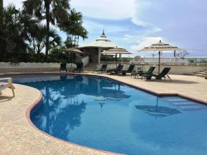 una gran piscina con sillas y sombrillas en Villa Guitarron gran terraza vista espectacular 6 huespedes piscina gigante en Acapulco