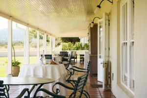 an outdoor patio with tables and chairs and windows at RiverBend Lodge in Addo