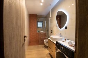 a bathroom with a sink and a toilet and a mirror at Lumera Urban Stay - New 2BR Home with Private Parking near Old Town in Chania +15 photos