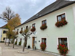 ein weißes Gebäude mit Blumenkästen an den Fenstern in der Unterkunft Zum Posthalter in Hemau