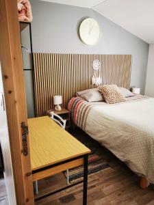 een slaapkamer met een bed en een klok aan de muur bij Studio - Chez Ana et Jonathan in Chantonnay
