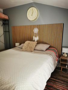 een slaapkamer met een groot bed met een klok aan de muur bij Studio - Chez Ana et Jonathan in Chantonnay