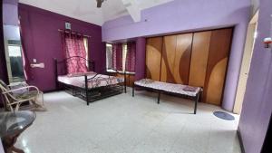 two beds in a room with purple walls at The Nest - Garwa in Miraj
