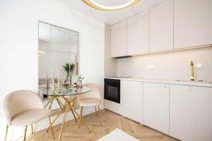 a white kitchen with a glass table and chairs at Apartmán Riviéra 3 in Banská Bystrica
