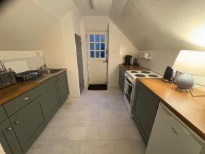 a kitchen with green cabinets and a stove top oven at Self Catering Apartment, Jurassic Coast/Dorset in Wareham