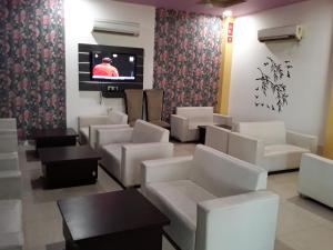 Una sala de espera con sillas blancas y un televisor de pantalla plana. en Clarks Collection Maanya, en Bareilly