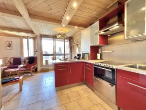 een keuken met rode kasten en een woonkamer bij SO206 Grand 2 pieces style chalet Les Menuires in Les Menuires