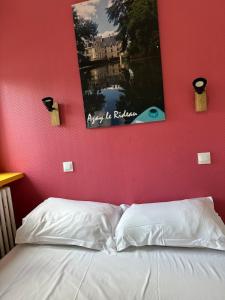 a bedroom with a red wall with a bed and a picture at Appartement 2 chambres au coeur de St Cyr avec parking privé in Saint-Cyr-sur-Loire