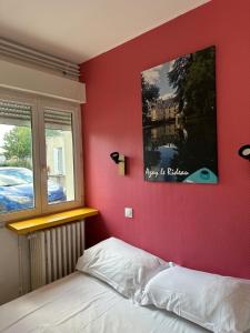 a bedroom with a red wall with a bed and a window at Appartement 2 chambres au coeur de St Cyr avec parking privé in Saint-Cyr-sur-Loire