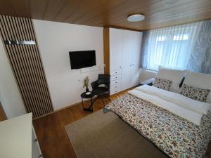 a bedroom with a bed and a tv on the wall at Ferienwohnung - zentral in Vorarlberg in Weiler