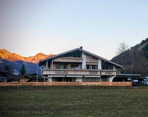 a large house in a field with mountains in the background at Hoamatl in Tannheim