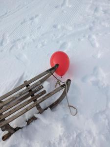a red balloon sitting next to a bench in the snow at Hoamatl in Tannheim