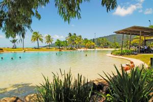 a swimming pool on a beach with people in the water at Whitsunday on The Beach in Airlie Beach