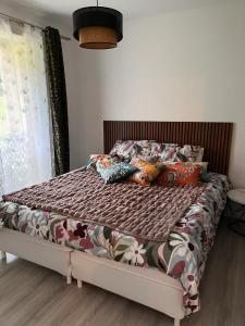 a bed with colorful pillows on it in a bedroom at Appartement convivial à Équemauville de 36 m² avec jardin in Équemauville