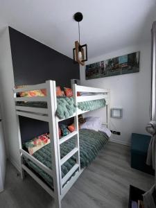 a bedroom with two bunk beds with green sheets at Appartement convivial à Équemauville de 36 m² avec jardin in Équemauville