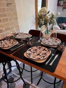 a table with plates and wine glasses on it at Appartement convivial à Équemauville de 36 m² avec jardin in Équemauville