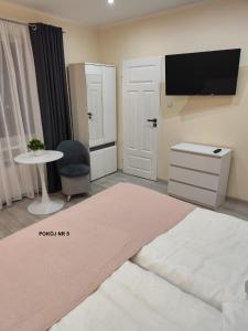 a room with a tv and a table and a bed at Willa Maja in Ciechocinek