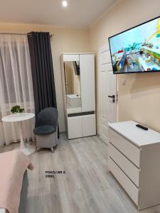 a living room with a tv and a white dresser at Willa Maja in Ciechocinek