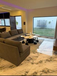 Una sala de estar con un sofá y mesas y una gran ventana. en شاليه داله العماريه1 بالكامل لك وأجواء ممتعه, en Abā al Kibāsh