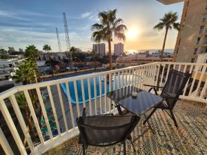 a balcony with a table and chairs and a pool at Palm Breeze - Las Americas in Playa de las Americas