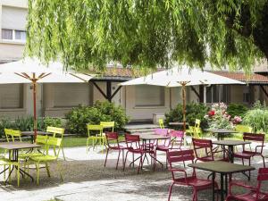 een groep tafels en stoelen met parasols bij ibis Styles Nancy Centre Gare in Nancy