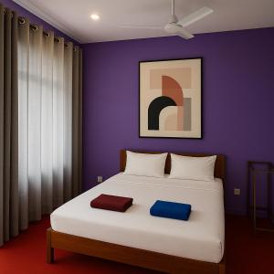 ein Schlafzimmer mit einem weißen Bett und einer lila Wand in der Unterkunft Eros Green House in Unawatuna