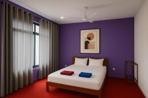 ein Schlafzimmer mit einem Bett mit einer lila Wand in der Unterkunft Eros Green House in Unawatuna