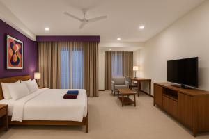 ein Hotelzimmer mit einem Bett und einem Flachbildfernseher in der Unterkunft Eros Green House in Unawatuna