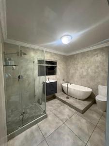 a bathroom with a tub and a shower and a toilet at Naliya Guest house in Cape Town
