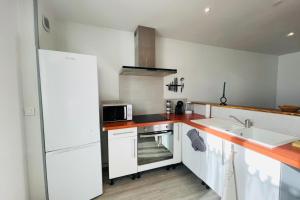 a kitchen with white cabinets and a sink and a microwave at La Maison de la Brousse in Brizambourg