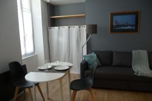 ein Wohnzimmer mit einer Couch und einem Tisch mit Stühlen in der Unterkunft Studio moderne rénové in Saint-Jean-dʼAngély + 3 Fotos