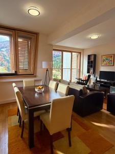 a living room with a table and chairs and a piano at Apartman Kadic in Bjelašnica +18 photos