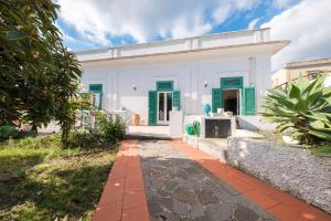a white house with green shutters and a pathway at La Casa Bianca in Marina