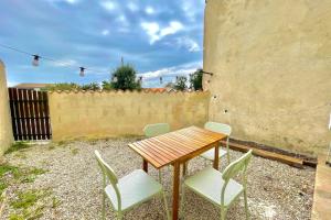 Una mesa y sillas con una mesa de madera y una cerca en La Touzetterie avec SPA-cour privée, en Saint-Jean-dʼAngély