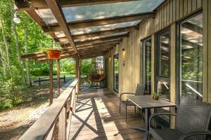 Un porche de madera con una mesa y sillas. en Meža māja, en Zaķumuiža